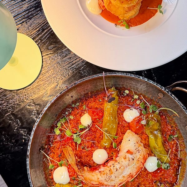 Two gourmet shrimp dishes on a dark table, one with fried shrimp, the other with a large grilled prawn.
