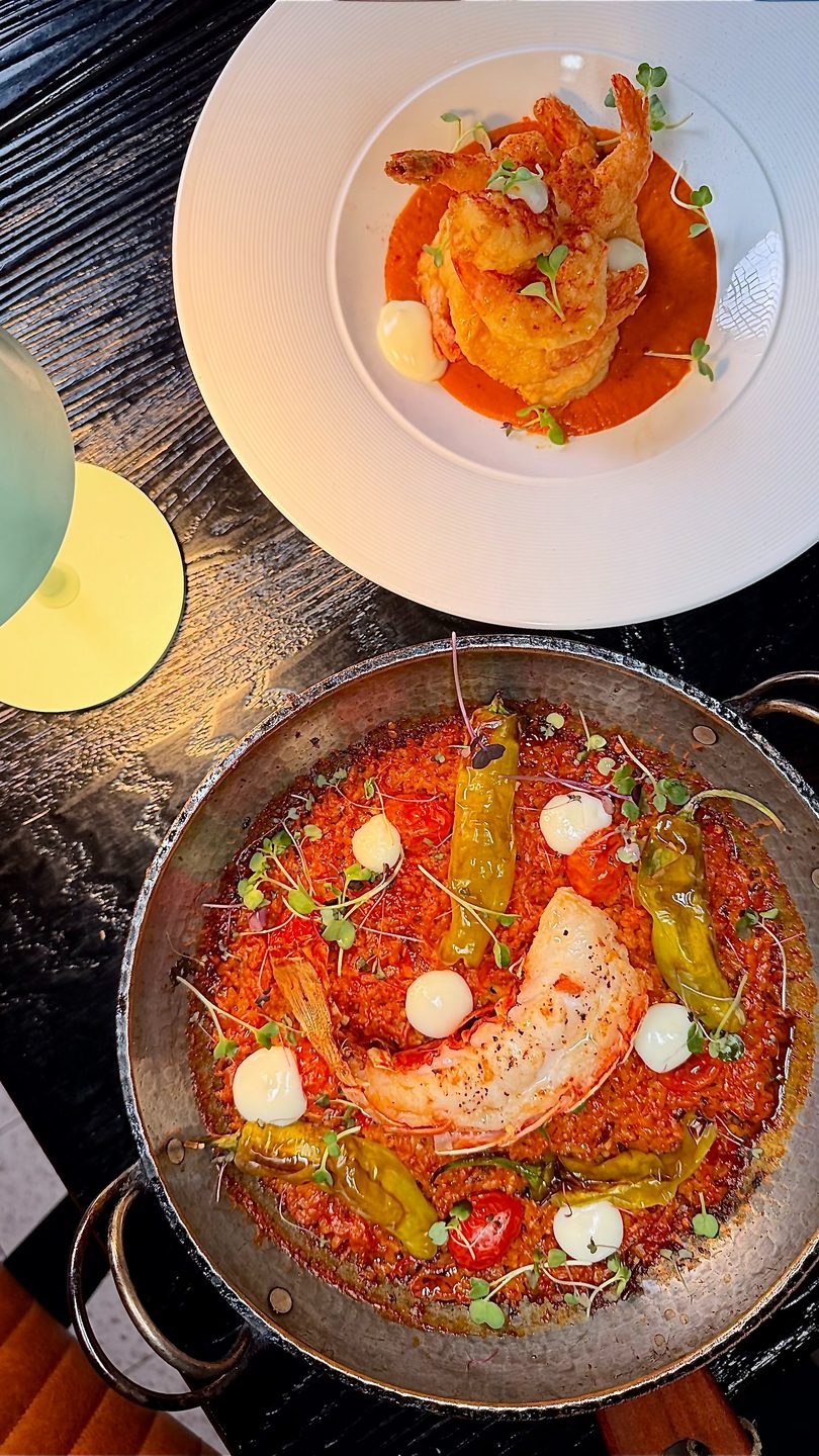 Two gourmet shrimp dishes on a dark table, one with fried shrimp, the other with a large grilled prawn.